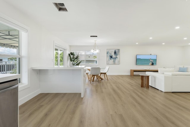 unfurnished dining area with a chandelier, light wood-type flooring, baseboards, and recessed lighting