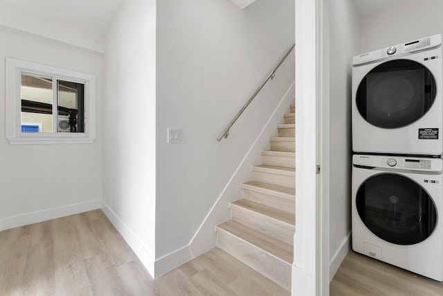 laundry area featuring laundry area, light wood-style flooring, baseboards, and stacked washer / dryer