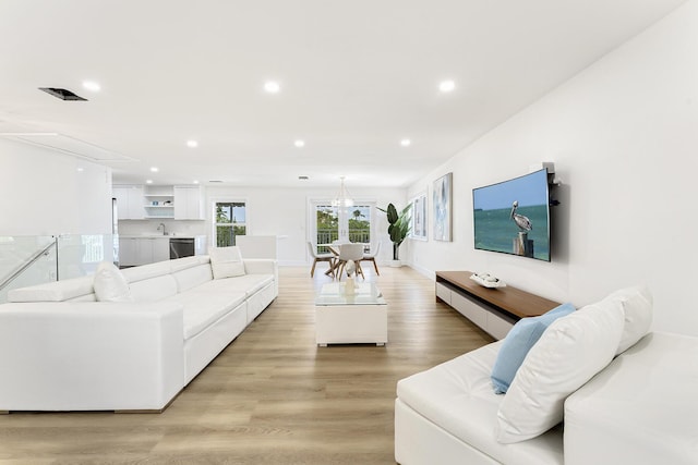 living room featuring a chandelier, light wood-type flooring, baseboards, and recessed lighting