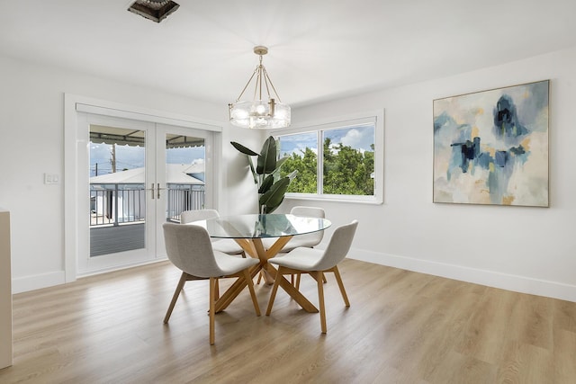 dining space with a notable chandelier, french doors, light wood-style flooring, and baseboards