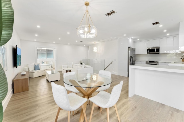 dining space featuring a chandelier, light wood-type flooring, visible vents, and recessed lighting