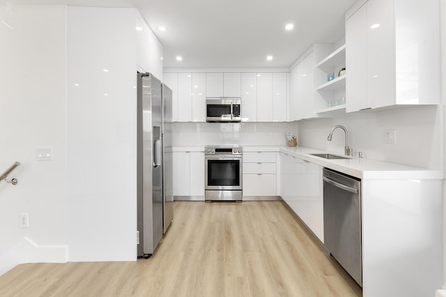 kitchen featuring stainless steel appliances, light countertops, white cabinetry, open shelves, and a sink