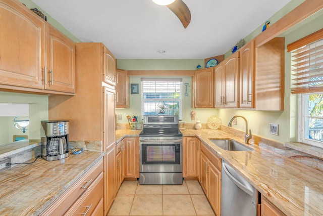 kitchen with light tile patterned flooring, light stone counters, a sink, light brown cabinets, and stainless steel appliances