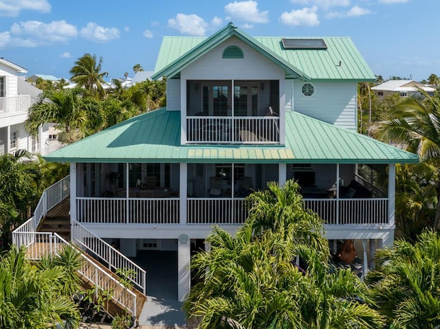 back of house with a sunroom, a standing seam roof, stairway, and metal roof