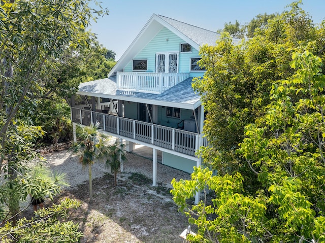 rear view of property with a balcony and roof with shingles