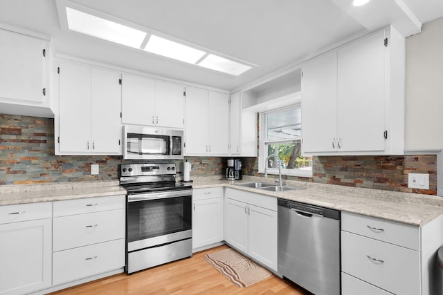 31034 Hollerich Dr, Big Pine, FL 33043 - kitchen featuring stainless steel appliances, tasteful backsplash, white cabinets, and light wood-style flooring