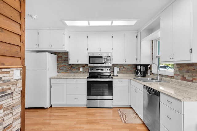 31034 Hollerich Dr, Big Pine, FL 33043 - kitchen featuring appliances with stainless steel finishes, white cabinetry, tasteful backsplash, and light wood finished floors