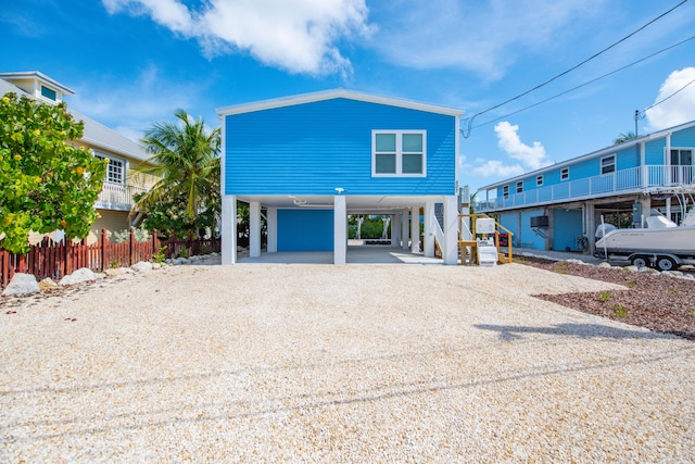 coastal inspired home featuring driveway, fence, and a carport