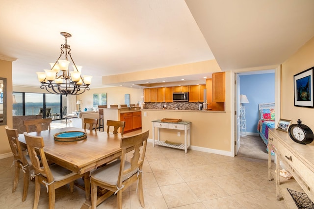 dining space featuring light tile patterned floors, recessed lighting, a water view, an inviting chandelier, and baseboards