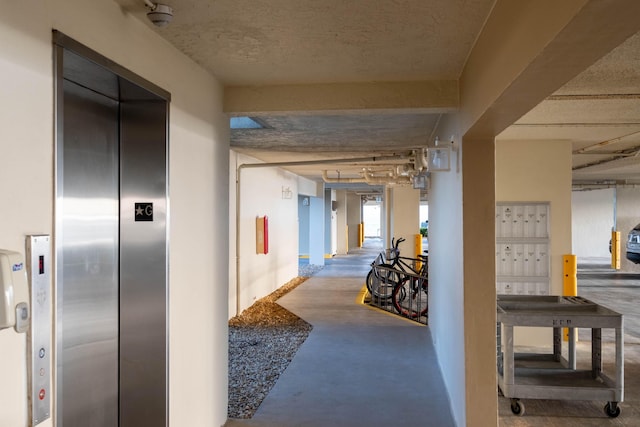 corridor with concrete floors, mail area, and elevator