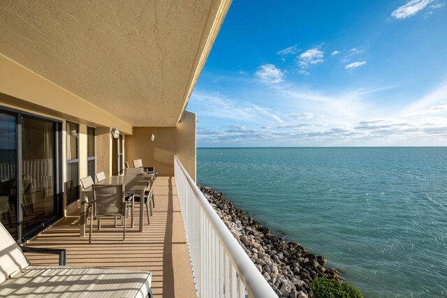 balcony featuring a water view and outdoor dining area