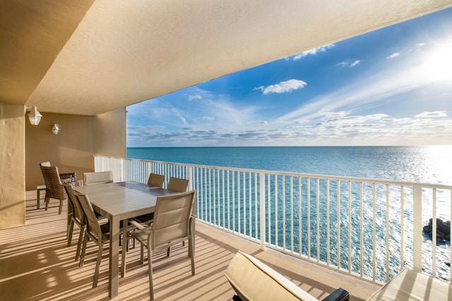 balcony with a water view and outdoor dining space