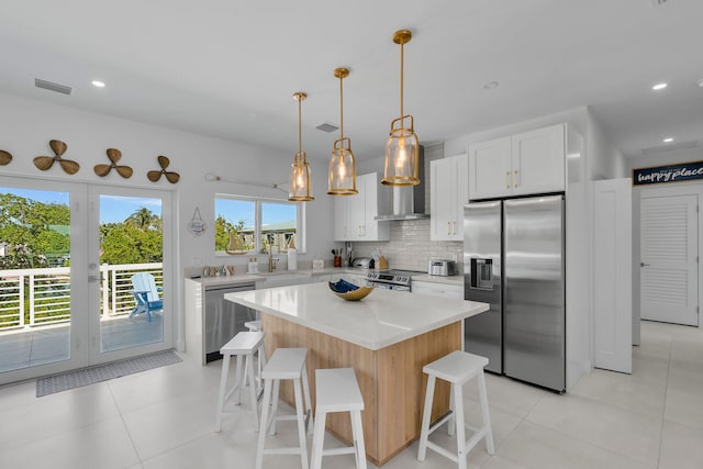 kitchen featuring white cabinets, a center island, stainless steel appliances, light countertops, and pendant lighting