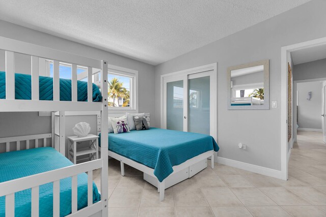 125 Cortez Dr, Islamorada, FL 33036 - bedroom with light tile patterned flooring, a textured ceiling, baseboards, and multiple windows