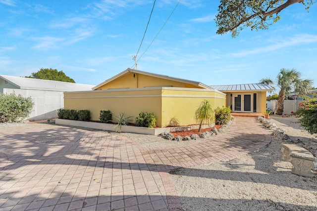 62 Sombrero Beach Rd, Marathon, FL 33050 - view of front of house with stucco siding, a patio, metal roof, french doors, and a standing seam roof
