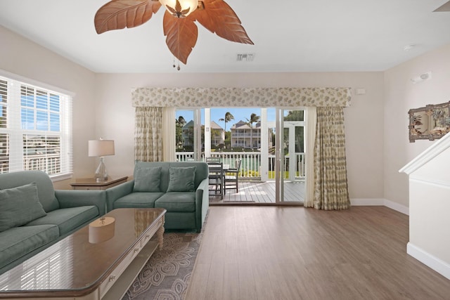 living room with visible vents, baseboards, wood finished floors, and a ceiling fan