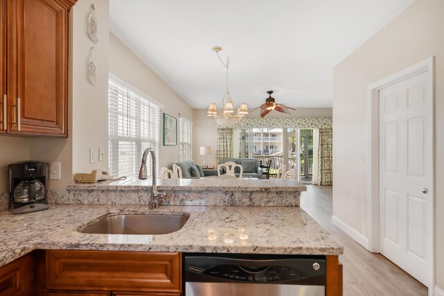 kitchen featuring open floor plan, light stone counters, brown cabinets, stainless steel dishwasher, and a sink