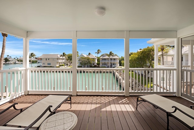 unfurnished sunroom featuring a wealth of natural light, a residential view, and a water view