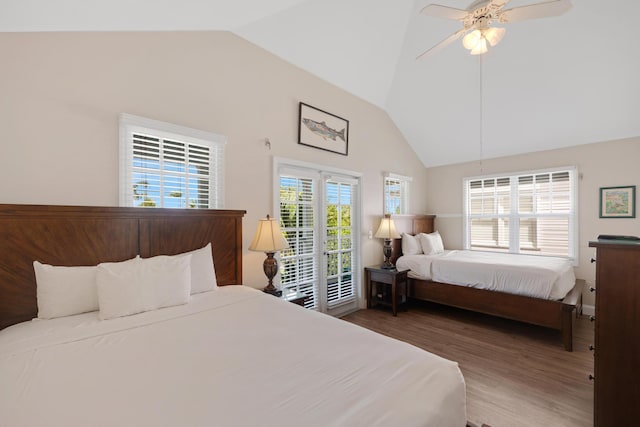 bedroom with access to exterior, high vaulted ceiling, a ceiling fan, and wood finished floors