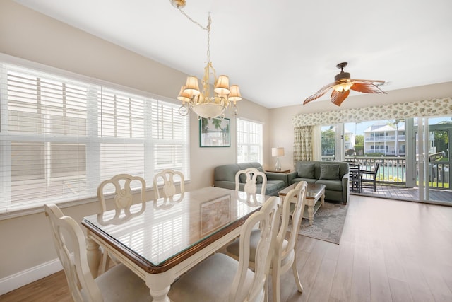 dining space with ceiling fan with notable chandelier, baseboards, and light wood-style floors