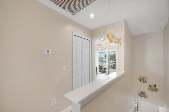 hallway with recessed lighting, visible vents, baseboards, and an upstairs landing