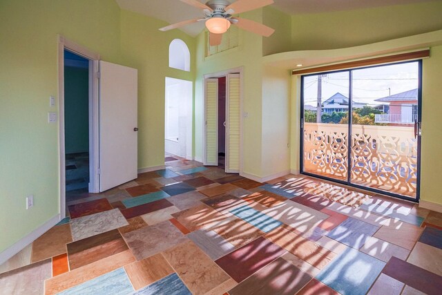 unfurnished bedroom with a closet, a high ceiling, baseboards, and a ceiling fan