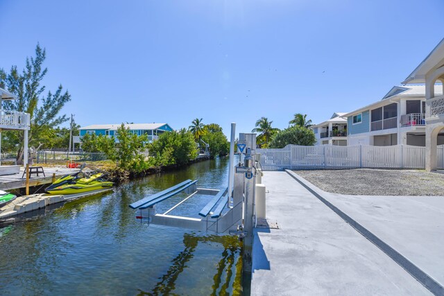 dock area featuring a water view, fence, and boat lift