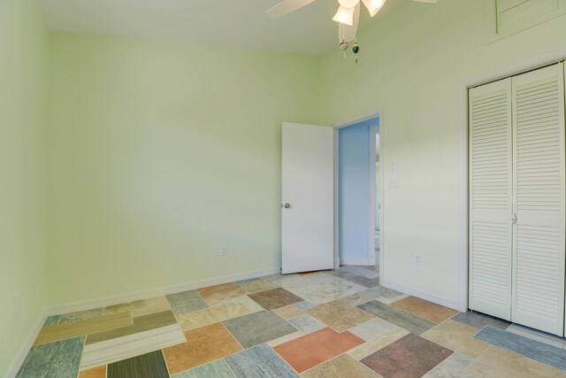 unfurnished bedroom featuring a ceiling fan, stone finish flooring, baseboards, and a closet