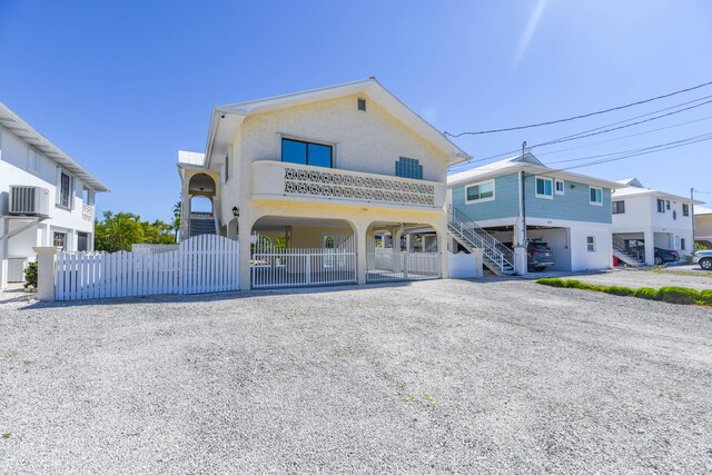 view of front of home featuring a fenced front yard, driveway, stairway, and stucco siding