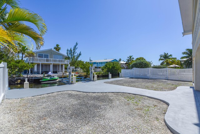 view of yard featuring a water view, a dock, and fence