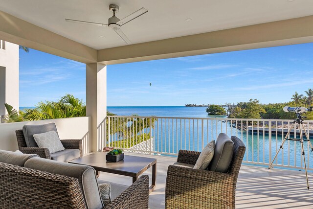 balcony with a ceiling fan, a water view, and an outdoor living space