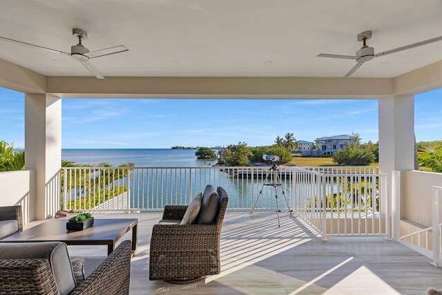 wooden terrace featuring a water view, ceiling fan, and an outdoor living space