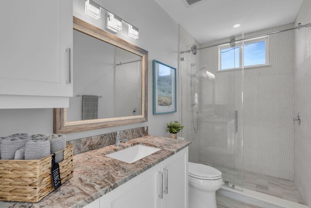 full bath with a stall shower, vanity, and toilet