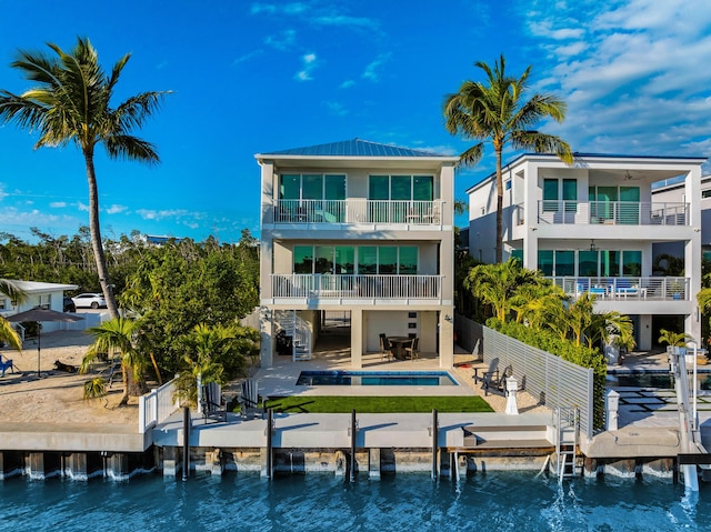 back of property featuring a water view, fence private yard, an outdoor pool, and a patio