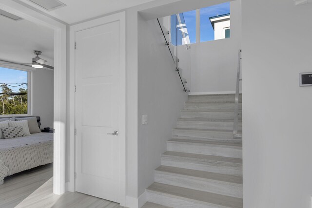 staircase with ceiling fan, wood finished floors, and visible vents