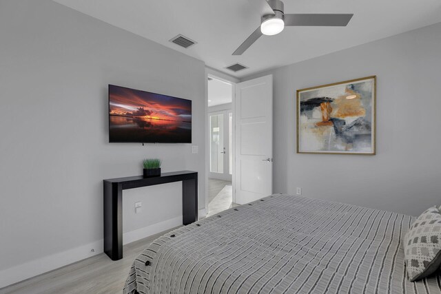 bedroom with light wood finished floors, a ceiling fan, visible vents, and baseboards