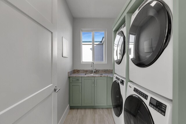 laundry area with a sink, cabinet space, baseboards, and stacked washer / drying machine