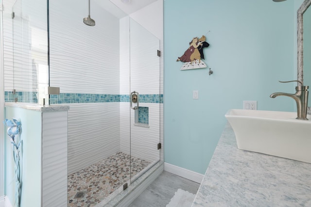 bathroom featuring a stall shower, a sink, and baseboards