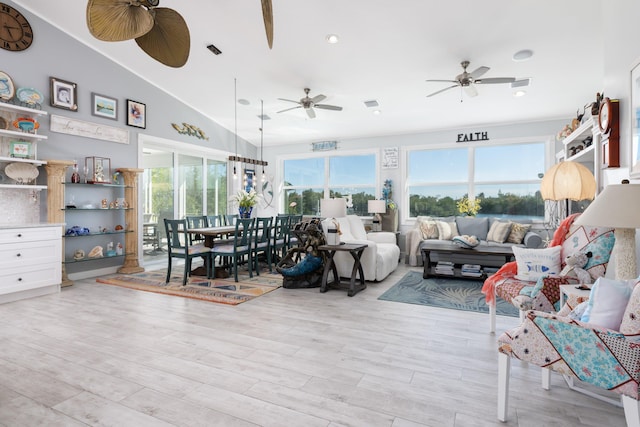 living area featuring lofted ceiling, light wood-style flooring, visible vents, and ceiling fan