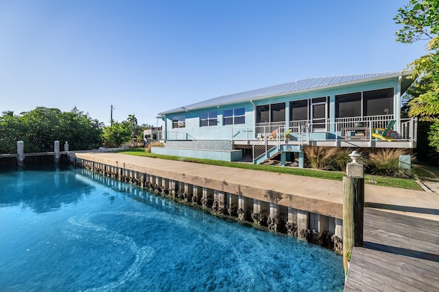 rear view of property with metal roof, a water view, and a sunroom