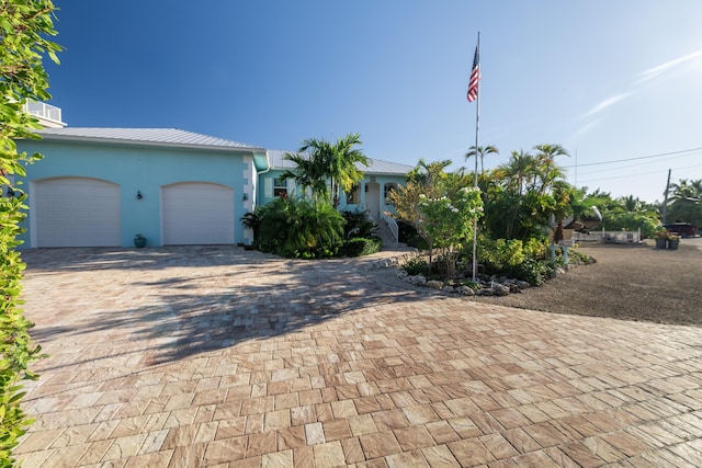 view of front of property featuring metal roof, decorative driveway, an attached garage, and stucco siding