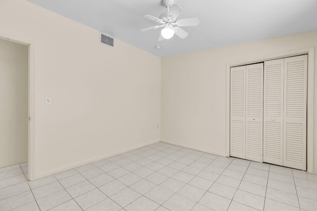 unfurnished bedroom featuring light tile patterned floors, a ceiling fan, visible vents, baseboards, and a closet