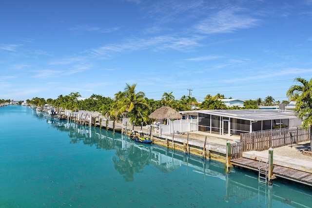 exterior space with fence, a water view, a sunroom, and a boat dock