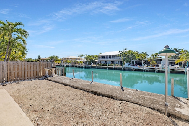 view of swimming pool with fence, a boat dock, and a water view