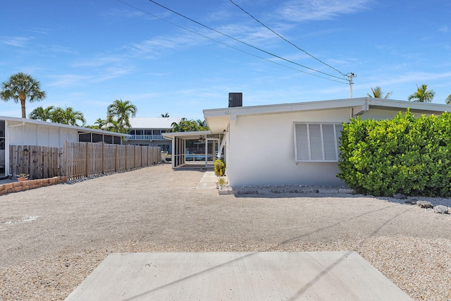 back of house featuring stucco siding, fence, and a sunroom