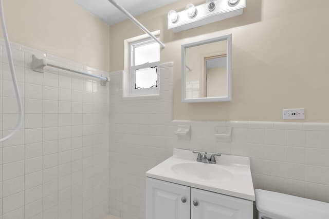 bathroom featuring a wainscoted wall, vanity, tiled shower, and tile walls