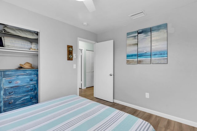 bedroom featuring ceiling fan, wood finished floors, visible vents, and baseboards