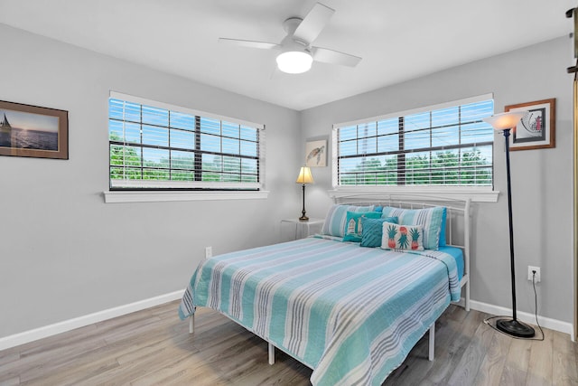 bedroom with multiple windows, ceiling fan, baseboards, and wood finished floors