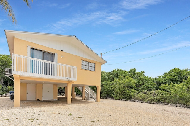 back of house with a carport, driveway, and stairs