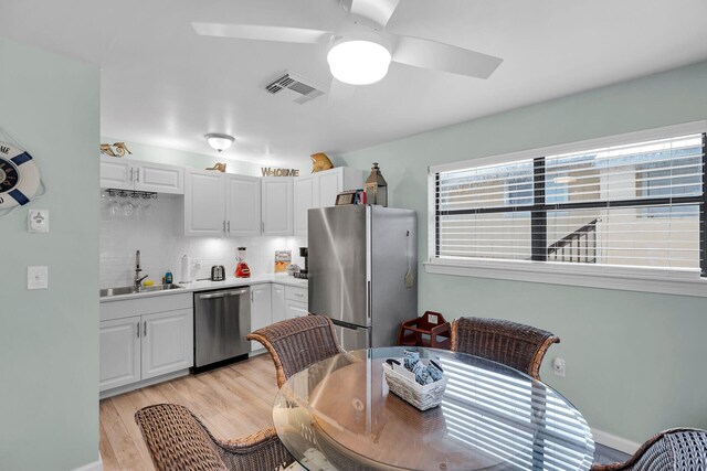 kitchen with stainless steel appliances, light countertops, visible vents, white cabinetry, and a sink